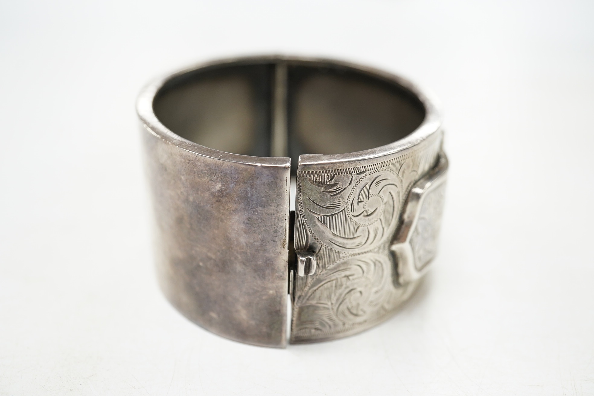 A George V engraved silver hinged bangle, with 'buckle' decoration, Kirwan & Co Ltd, Birmingham, 1913. Condition - poor to fair